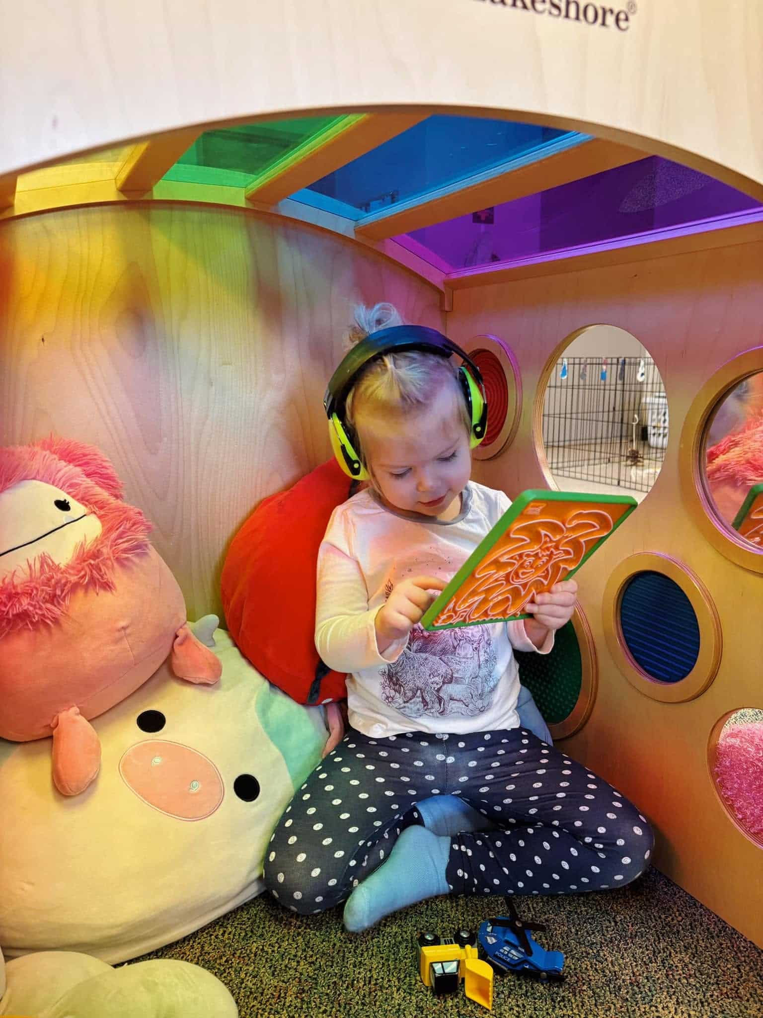 A child wears headphones and uses a visual activity card in a quiet classroom space