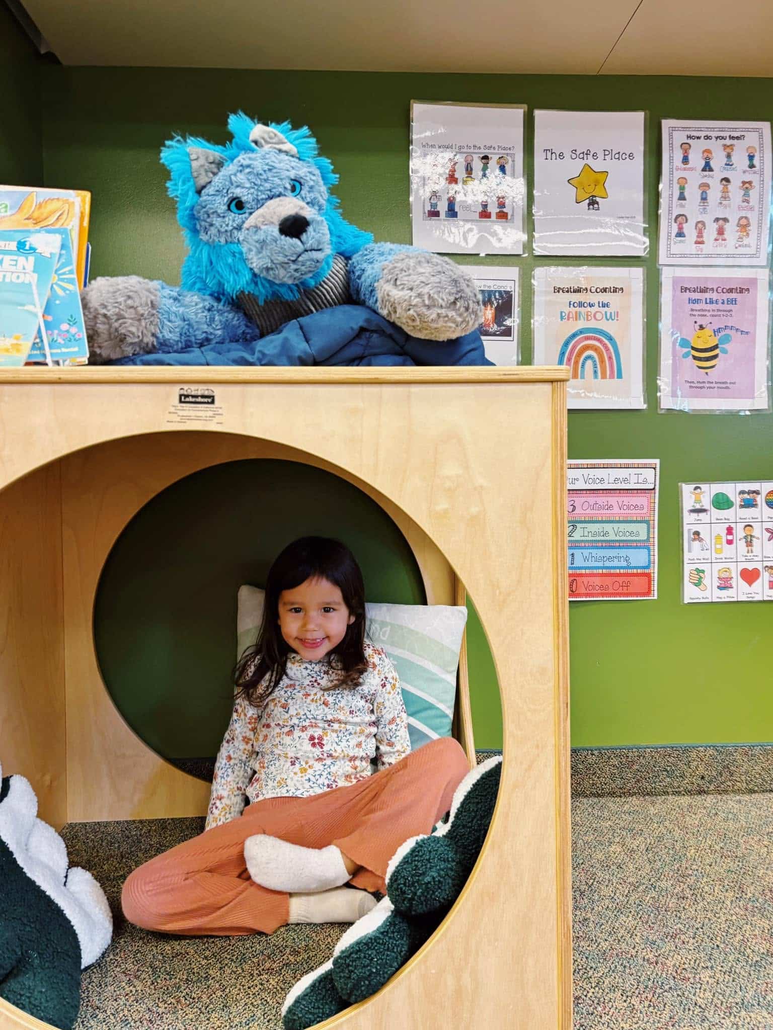 A child sits in Green Garden's Safe Place with comfort items and feeling visuals nearby