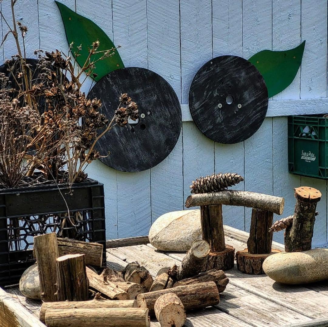Loose parts including branches, pinecones, stones, and wood pieces arranged outdoors