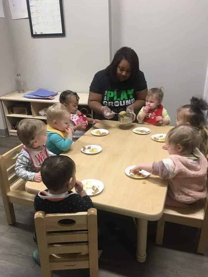 Ms. Shanea sitting with children during a meal
