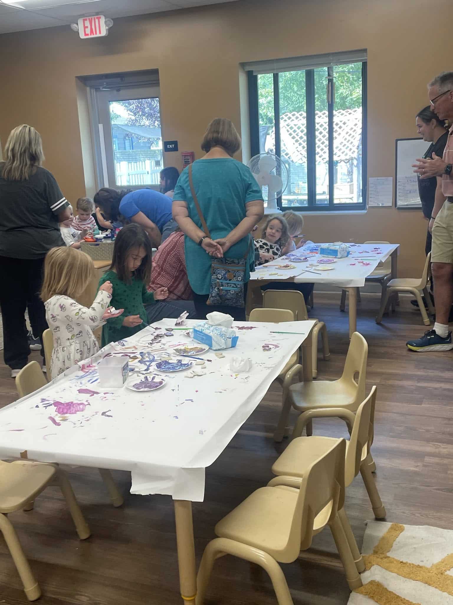 Children and family members making art together around classroom tables
