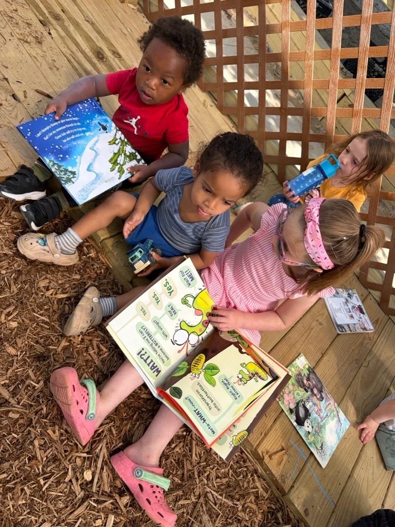 Children looking through books together in an outdoor wooden nook