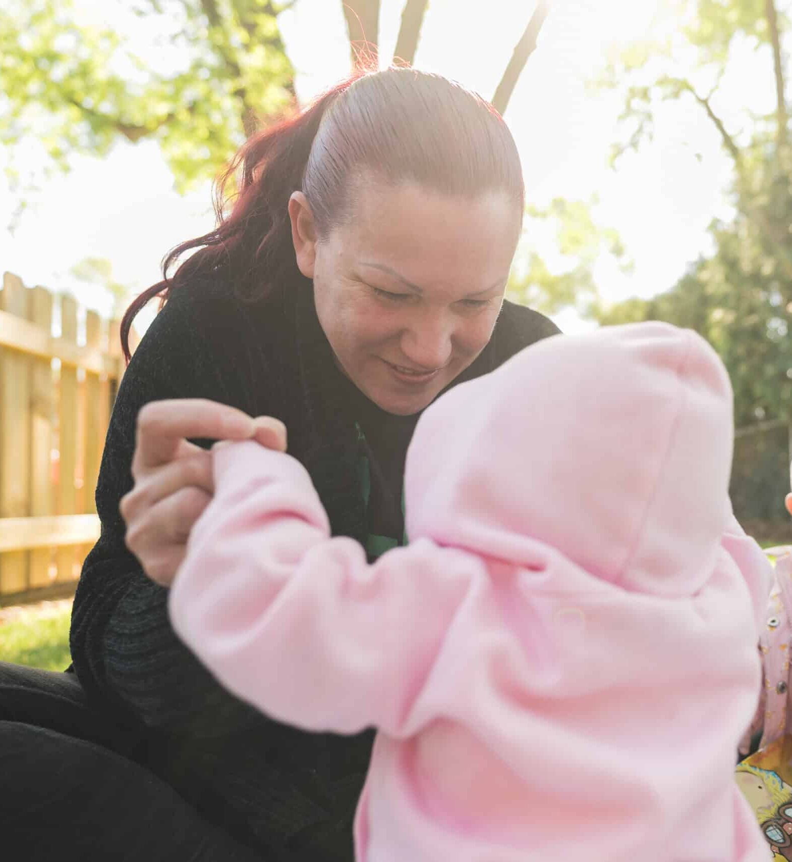 A Green Garden teacher connects with a baby outdoors
