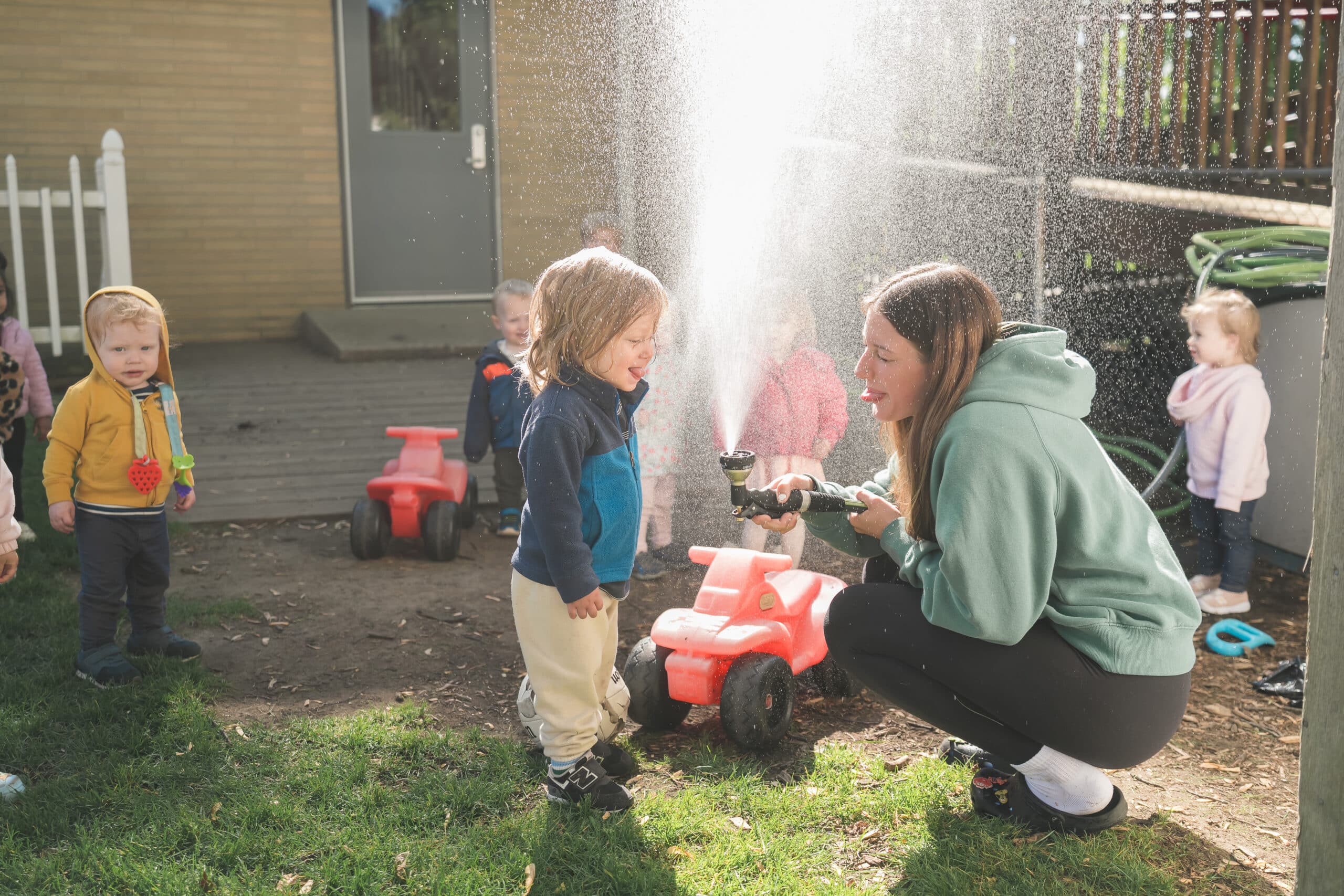 Teacher and children exploring water outdoors at Green Garden Clawson