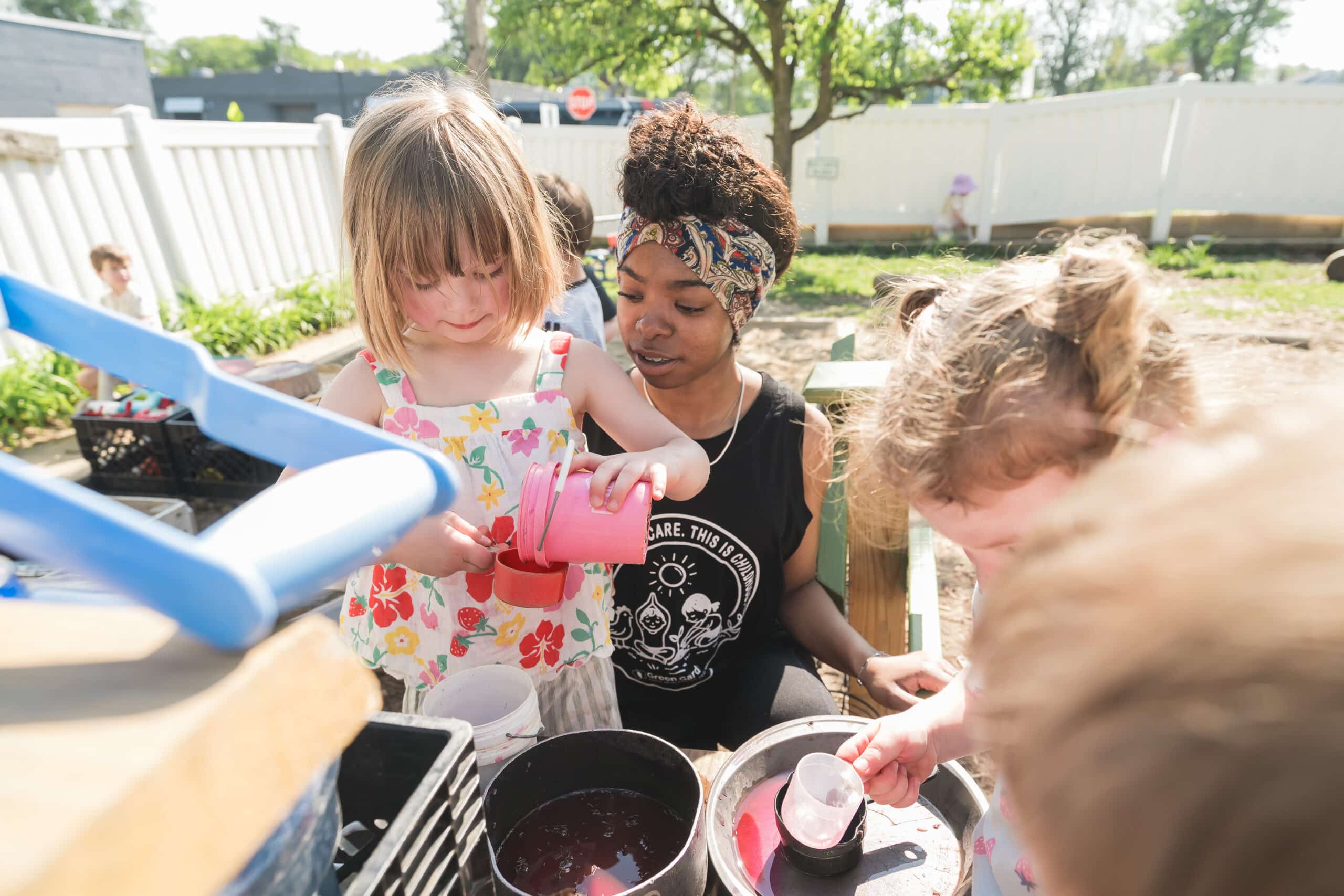 Ms. Autumn supporting children at an outdoor water table