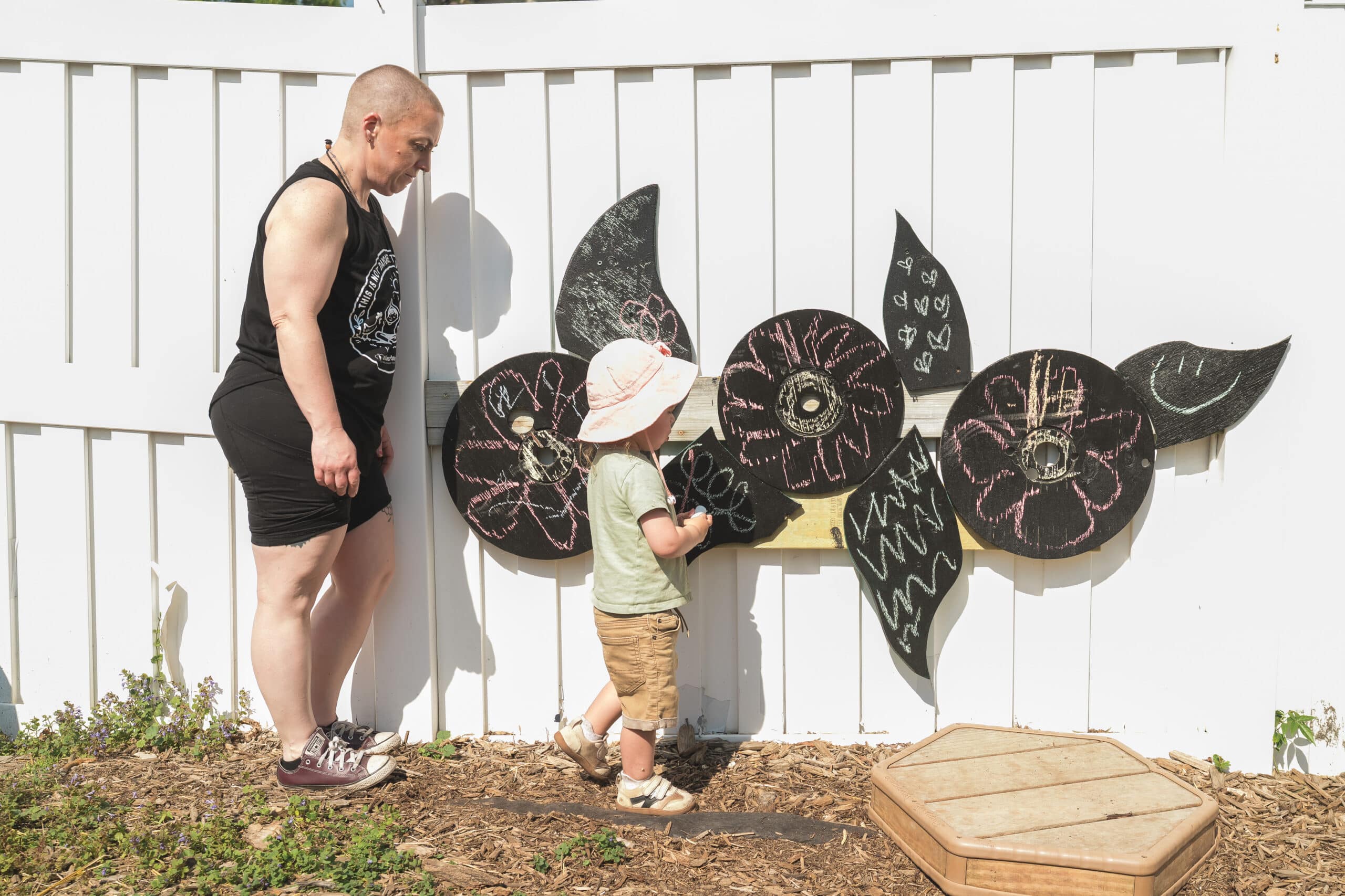 Ms. Becky with a child at the outdoor chalk board