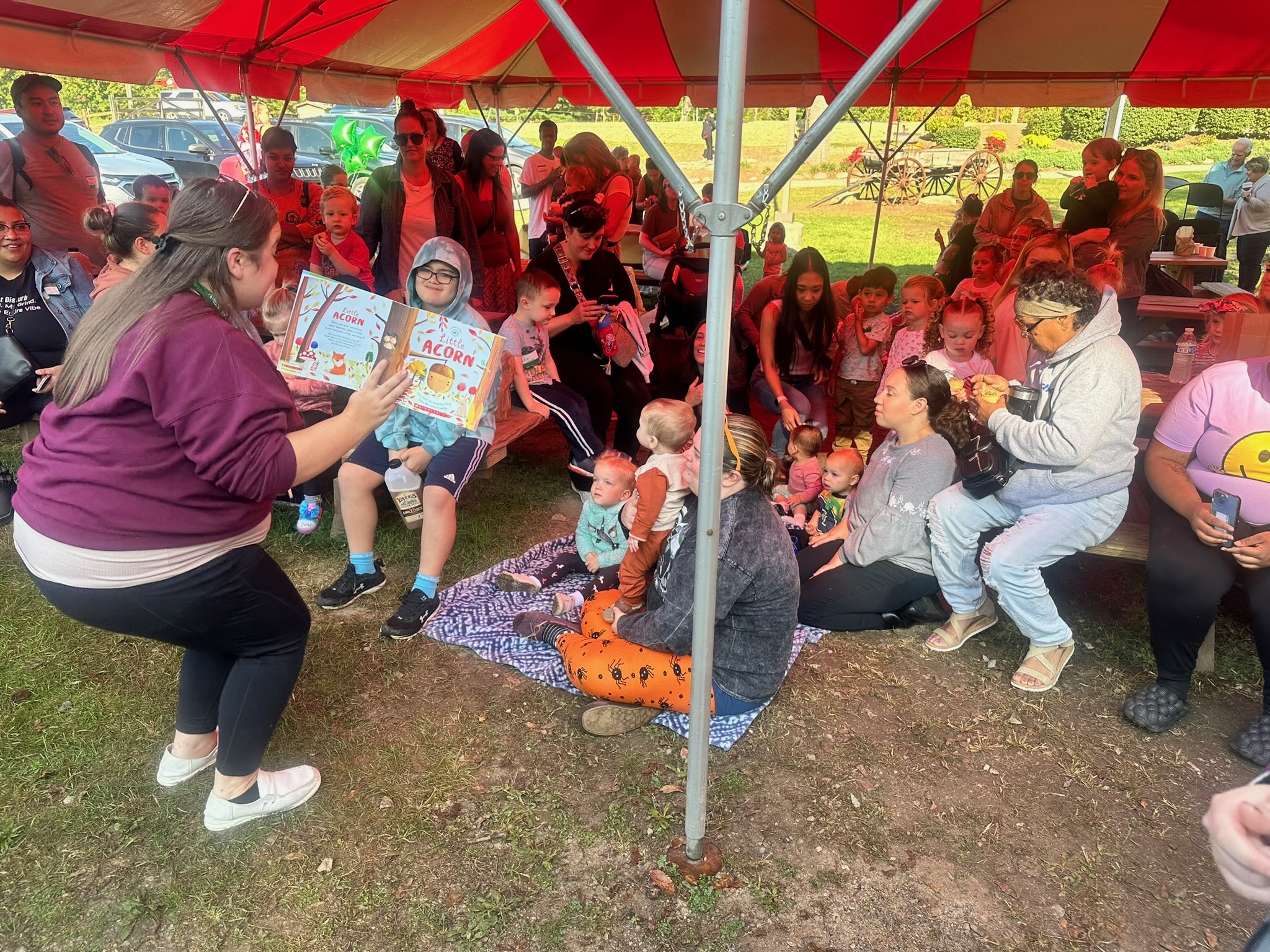 Families and children gathered beneath a canopy for a story together