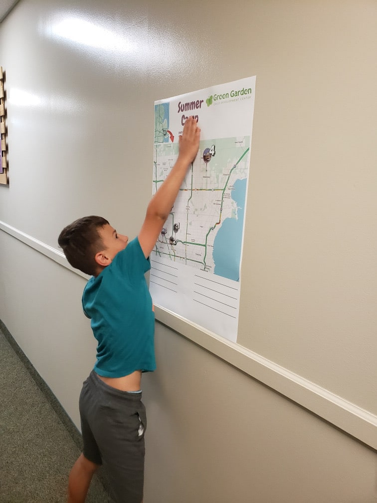 Camper points to a Green Garden summer camp map on the wall